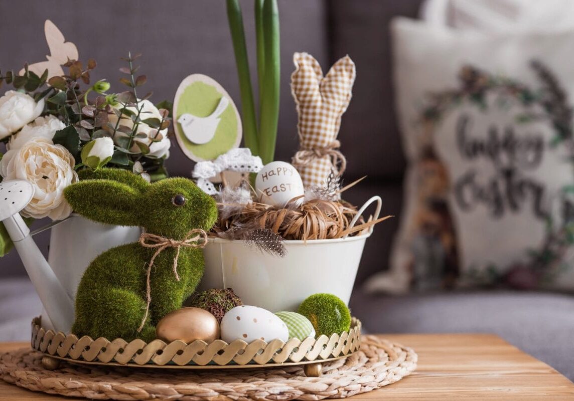 Rustic. White-green colors. Iron planters with Easter eggs, flowers, candles and rabbits in the living room interior on the table. The concept of home comfort in the bright holiday of Easter 2022.