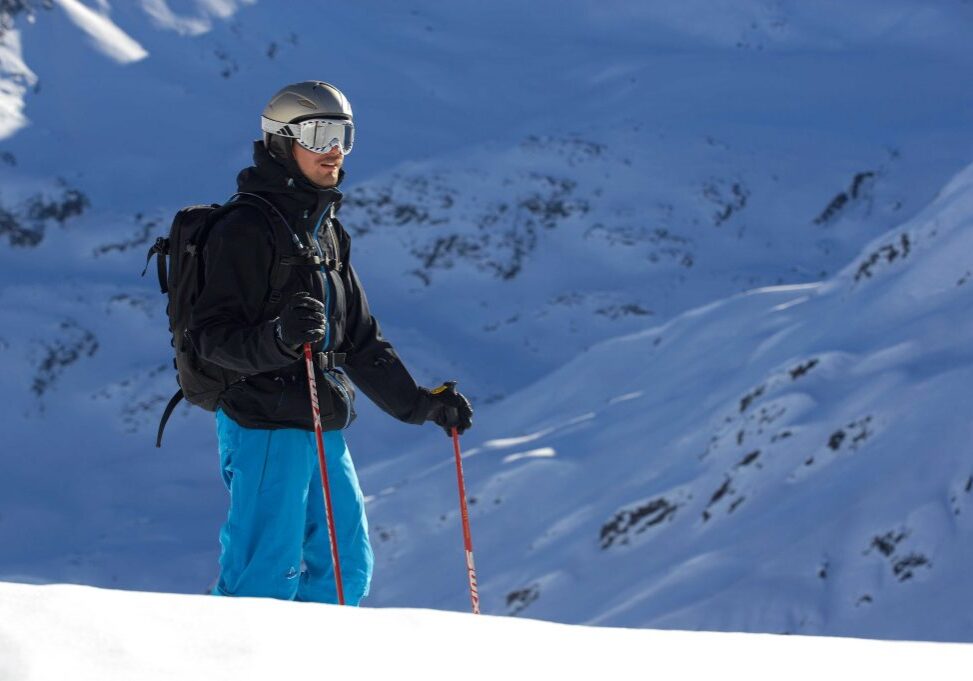 Man with a gold helmet and full ski gear asseses the snowe slopes near Stuben.
